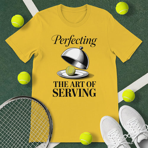 Yellow t-shirt with the text 'Perfecting THE ART OF SERVING' and a graphic of a tennis ball being served in a chef's cloche.