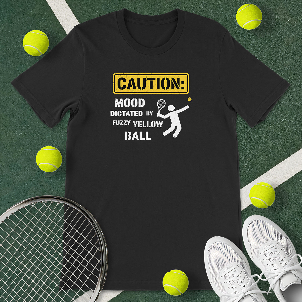 Black t-shirt with the text 'CAUTION: MOOD DICTATED BY FUZZY YELLOW BALL' and a graphic of a person serving.