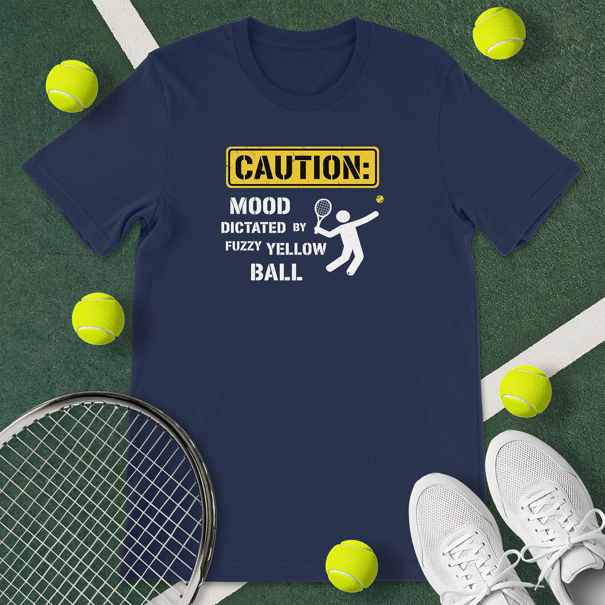 Navy blue t-shirt with the text 'CAUTION: MOOD DICTATED BY FUZZY YELLOW BALL' and a graphic of a person serving.