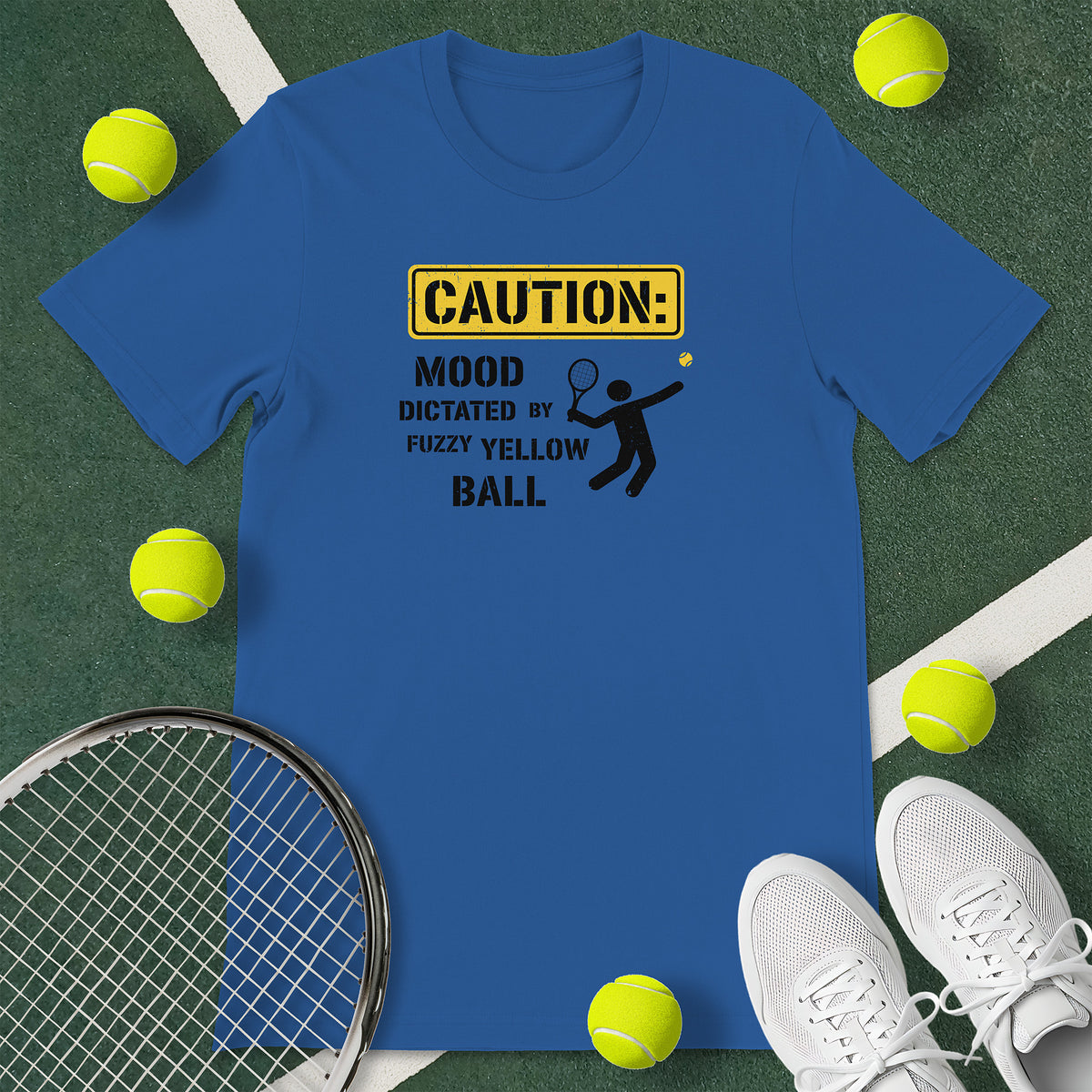 Royal blue t-shirt with the text 'CAUTION: MOOD DICTATED BY FUZZY YELLOW BALL' and a graphic of a person serving.