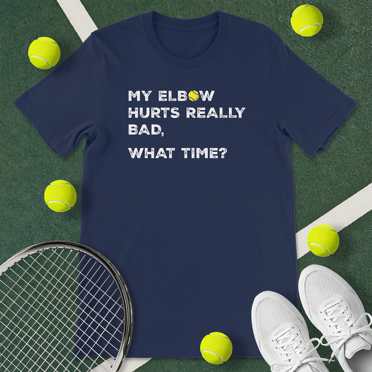 Navy blue t-shirt with the text 'MY ELBOW HURTS REALLY BAD, WHAT TIME?' and a graphic of a tennis ball.